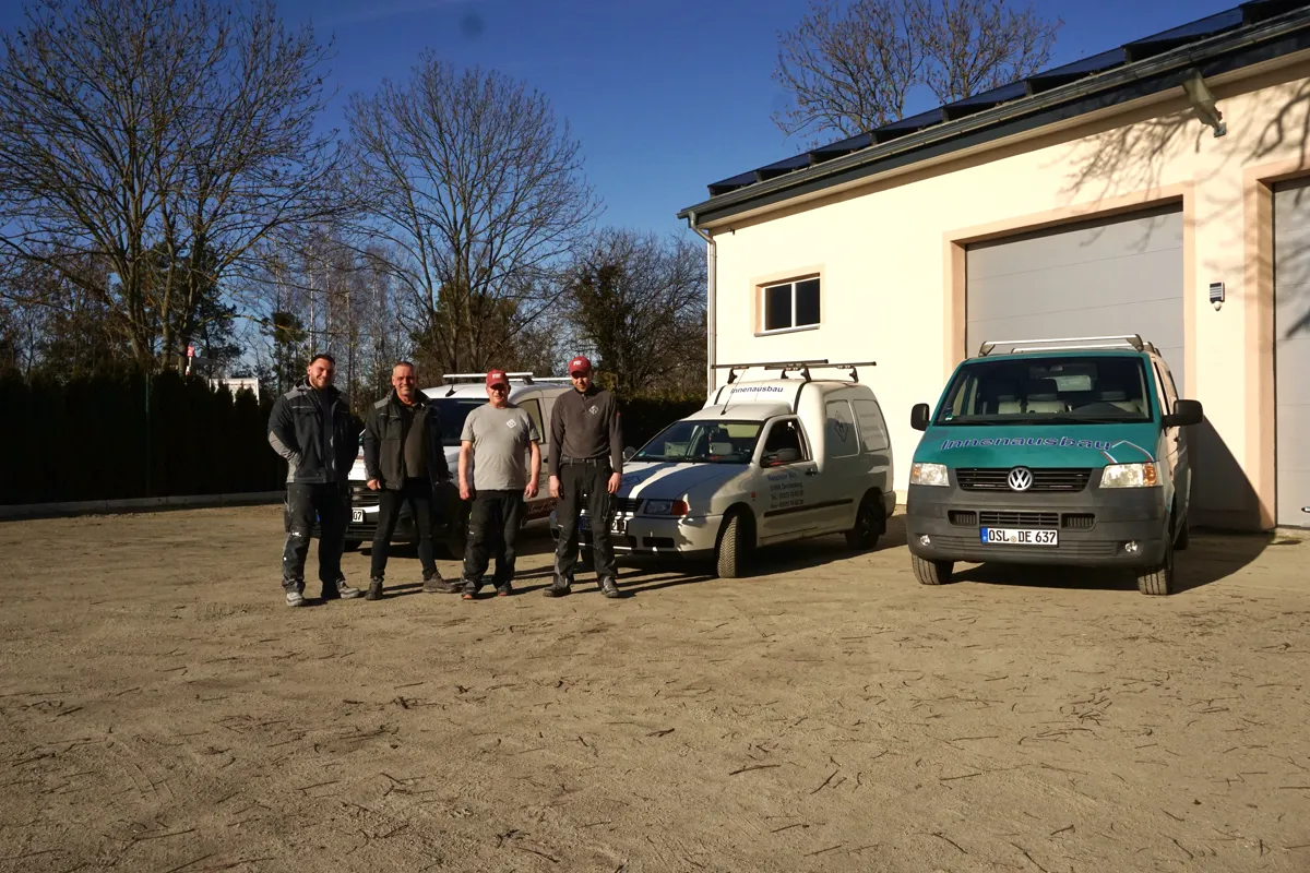 Das Team von Trockenbau Häusler vor den Firmenfahrzeugen